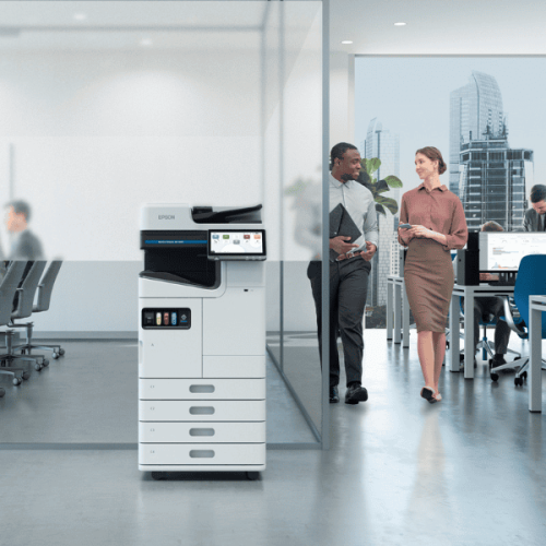 two people walking towards printer in busy office