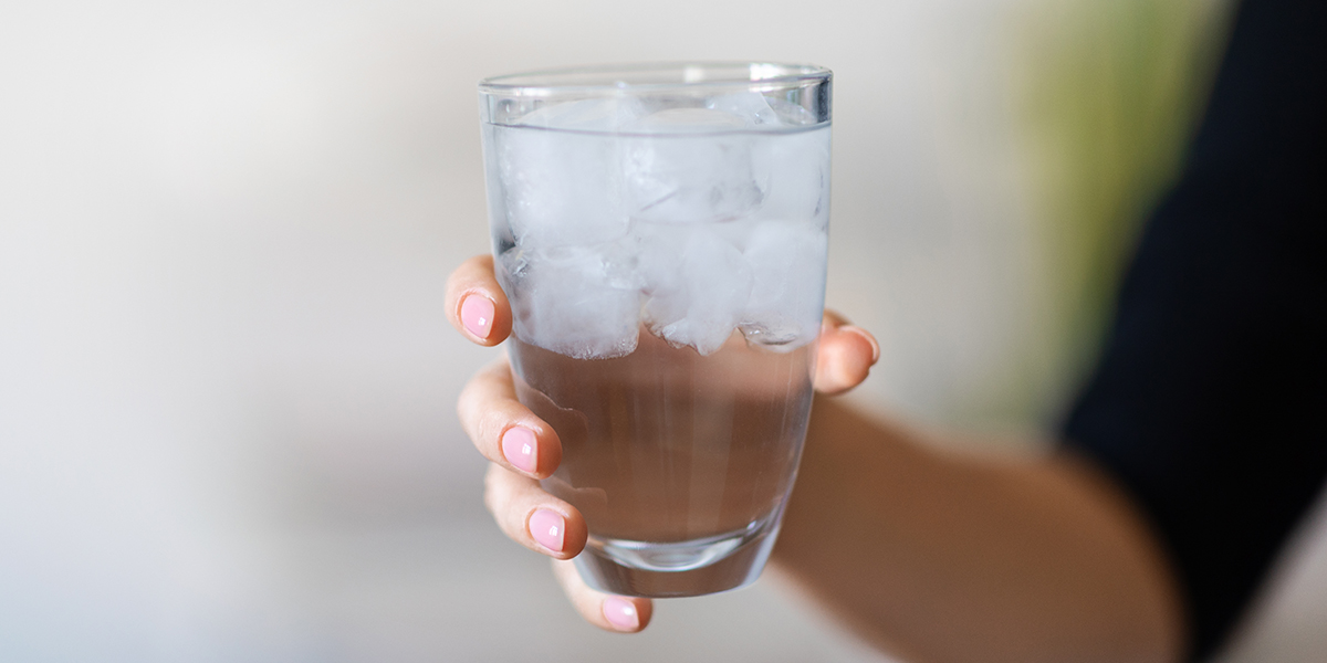 Glass Of Water With Ice In Hand Of Unrecognizable Woman